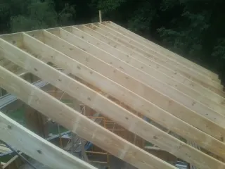 New roof rafters set over an addition before sheathing in Luverne