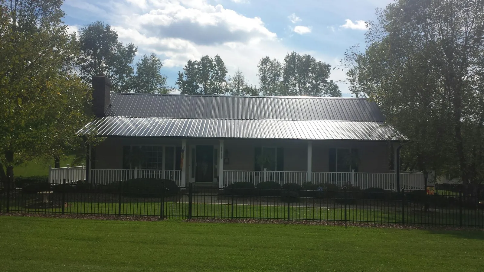 Gray metal roof on a brick ranch with a full width front porch — Gutter Guard Installation work by our crew in Luverne