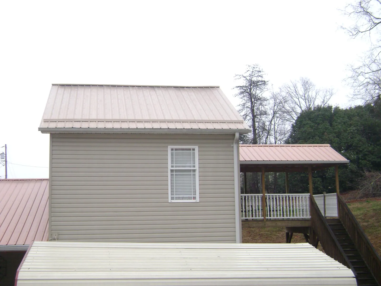 Tan metal roofs on a two story addition and attached porch, from a Roof Replacement job in Luverne